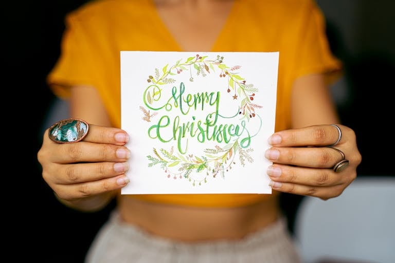 Bright and festive Christmas card held by hands against a blurred background.