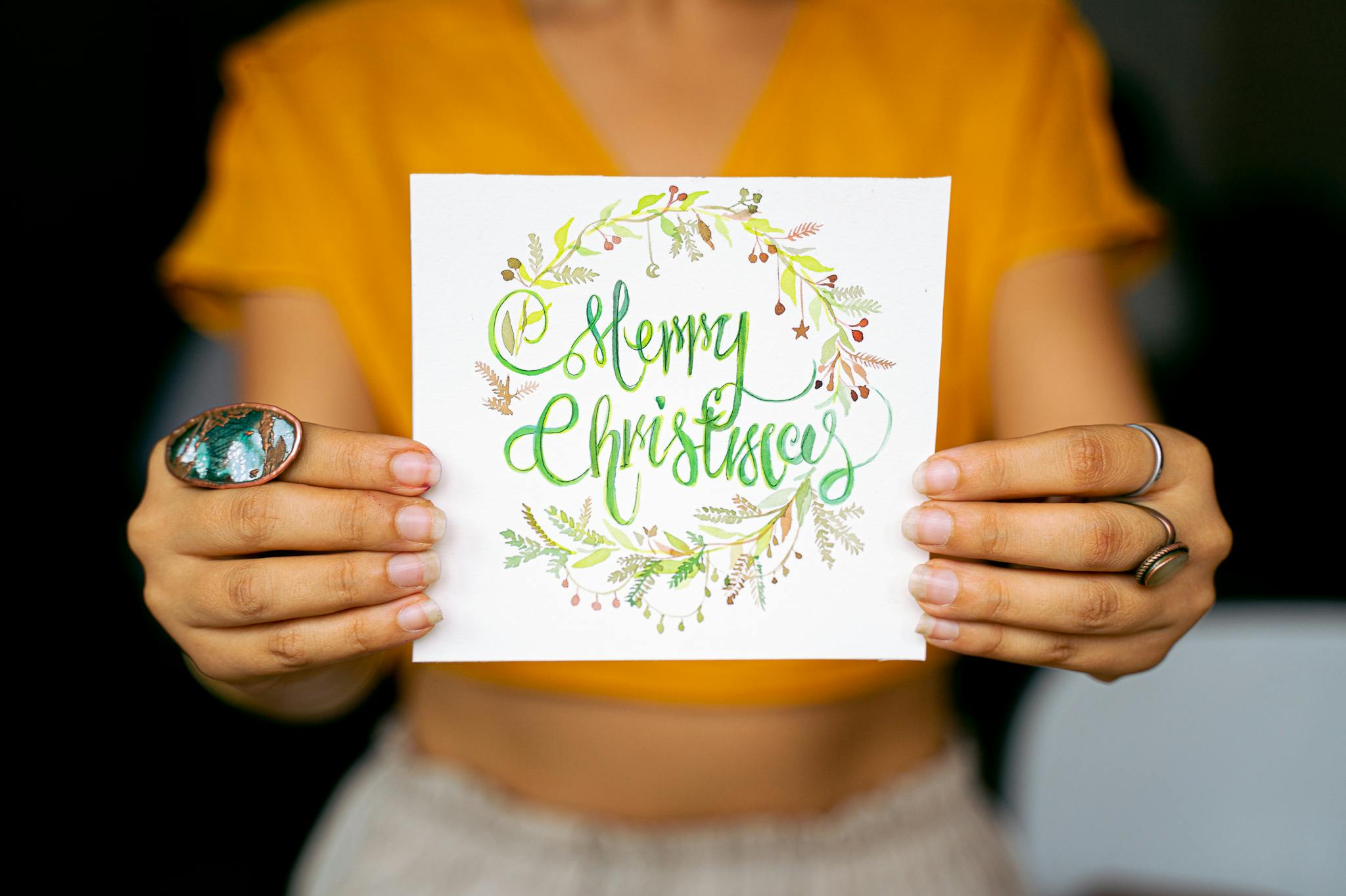 Bright and festive Christmas card held by hands against a blurred background.